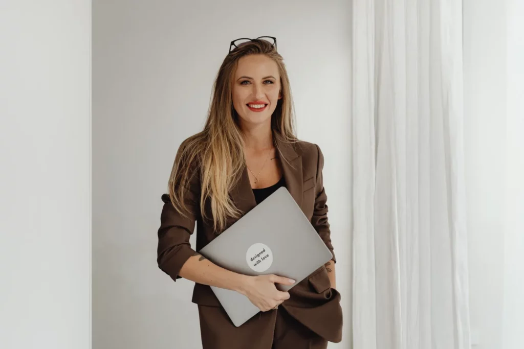 uśmiechnięta kobieta z laptopem pod ręką 