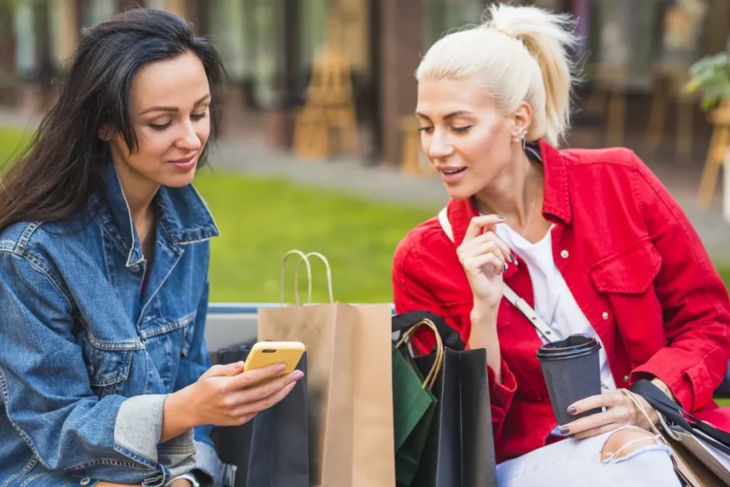 dwie kobiety oglądają na telefonie produkty 